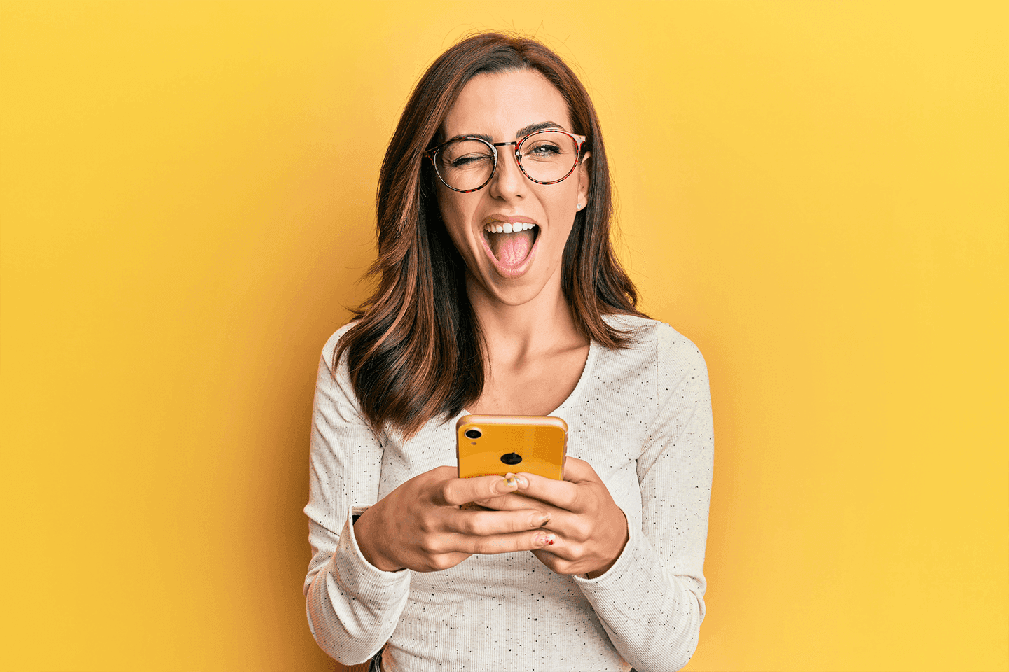 Lachende Frau mit Brille hält Smartphone.