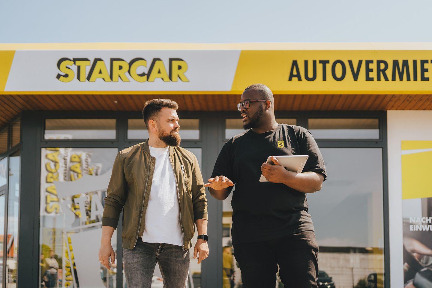 Zwei Männer unterhalten sich vor einem STARCAR-Station.