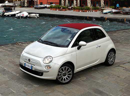Weißes Fiat 500c Cabrio, geparkt auf einer Steinkai am Wasser.