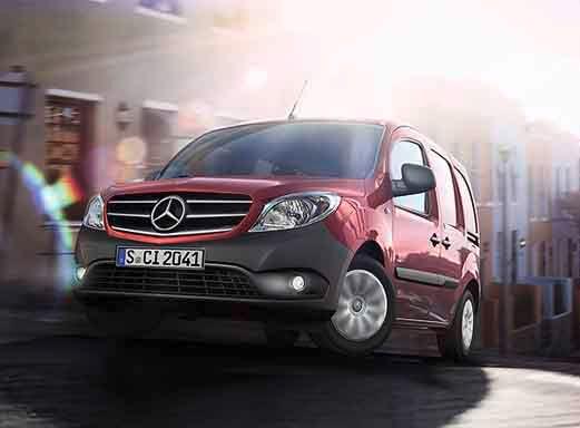 Roter Mercedes Benz Citan Mietwagen auf einer Stadtstraße.