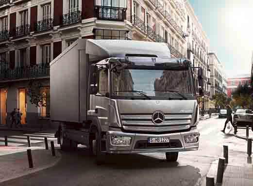 Silberner Mercedes Benz Atego LKW fährt auf einer Stadtstraße.