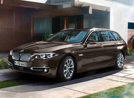 Dunkelbrauner BMW 5er Touring vor einem Gebäude.