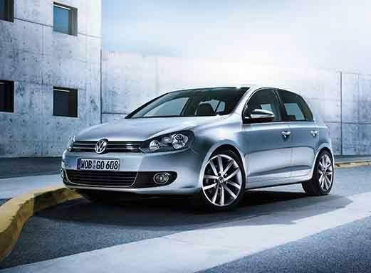 Silberner VW Golf Mietwagen auf Asphalt neben einer gelben Barriere.