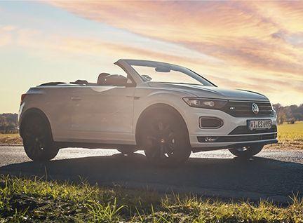 Weißes VW Cabrio, geparkt auf einer Straße bei Sonnenuntergang.