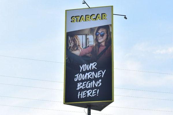 STARCAR Autovermietung Station Ramstein Banner mit einer Frau und dem Slogan 'Your journey begins here'.