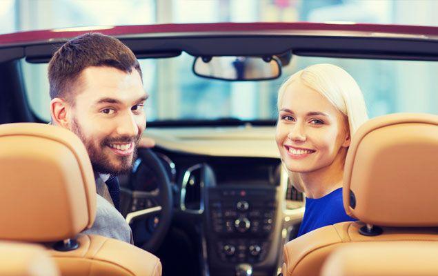 Zwei Autofahrer im Cabrio lächeln und genießen die Fahrt.