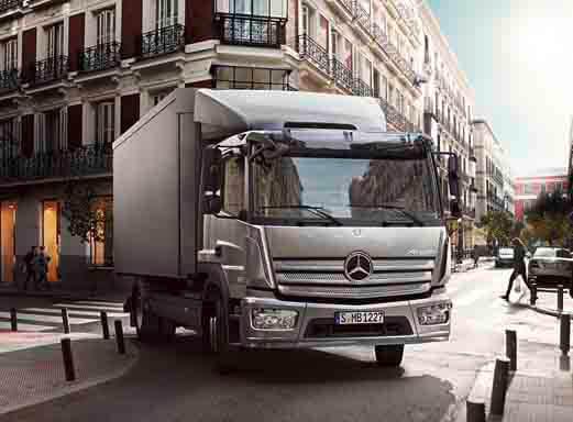 Silberner Mercedes-Benz Atego 7,5t Umzugswagen fährt auf einer Stadtstraße.