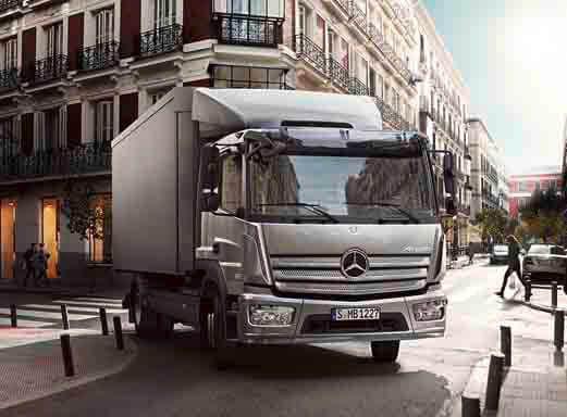 Silberner Mercedes Benz Atego LKW fährt auf einer Stadtstraße.