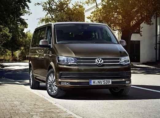 Dunkelgrauer VW Multivan auf sonniger Straße.